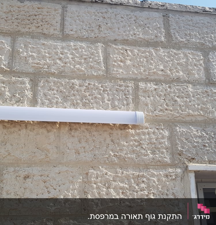 מנורת פלורסנט מותקנת על קיר אבן חיצוני